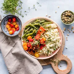 A plated meal with ceramic bowls and a wooden board on a linen cloth